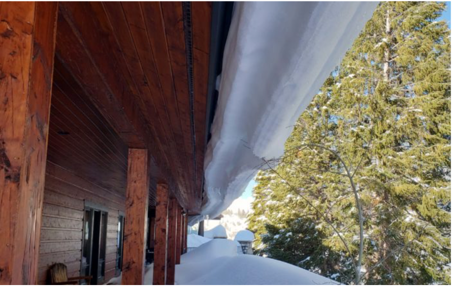 Monitoring heavy snow accumulation and thick ice buildup hanging over a home's gutter line.