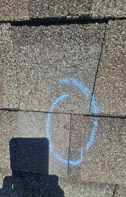 Marking hail damage on an asphalt shingle roof system during a professional roofing inspection.