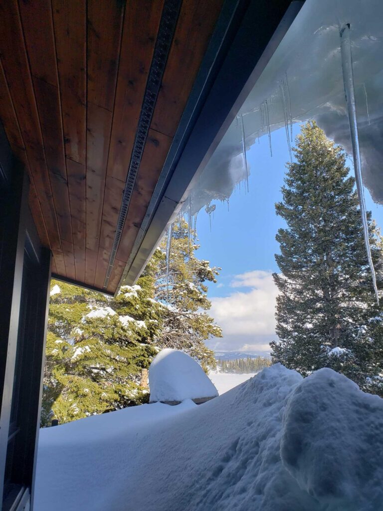 Snow-covered roof with icicles along the eaves.