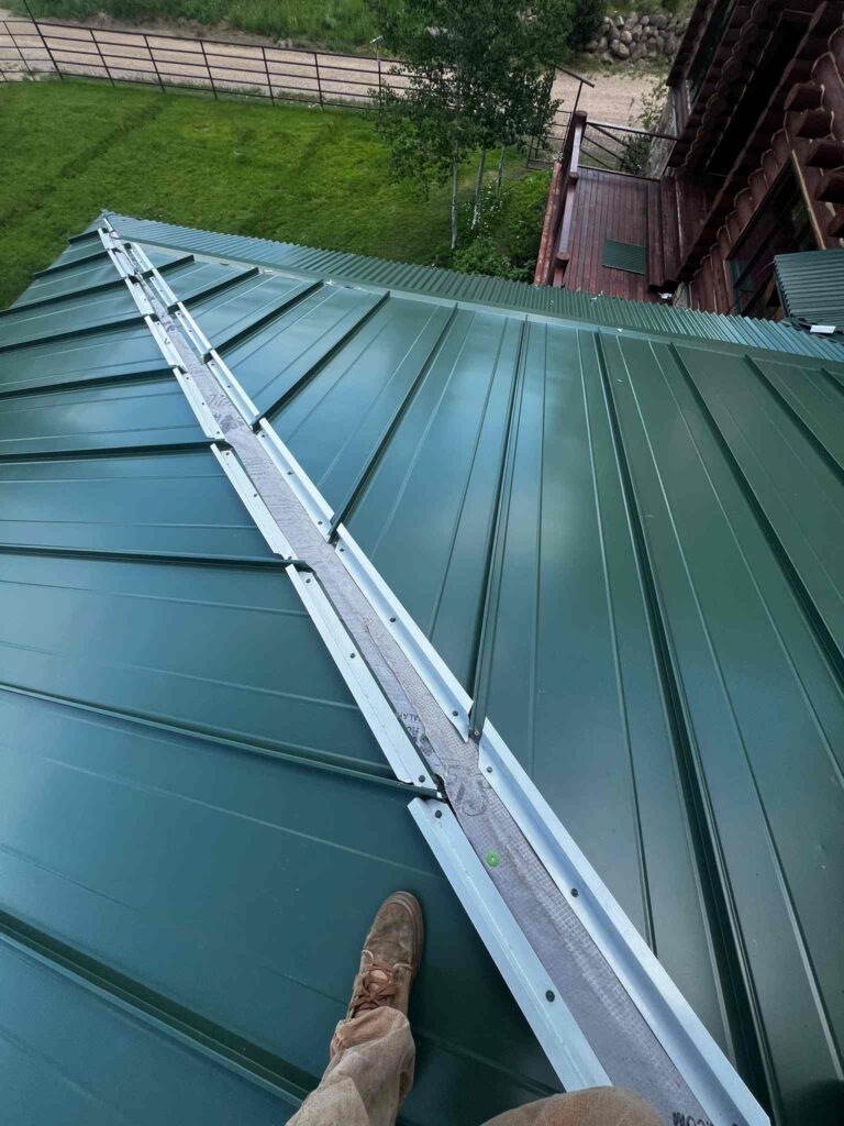 Close-up of a dark green standing seam metal roof installation.